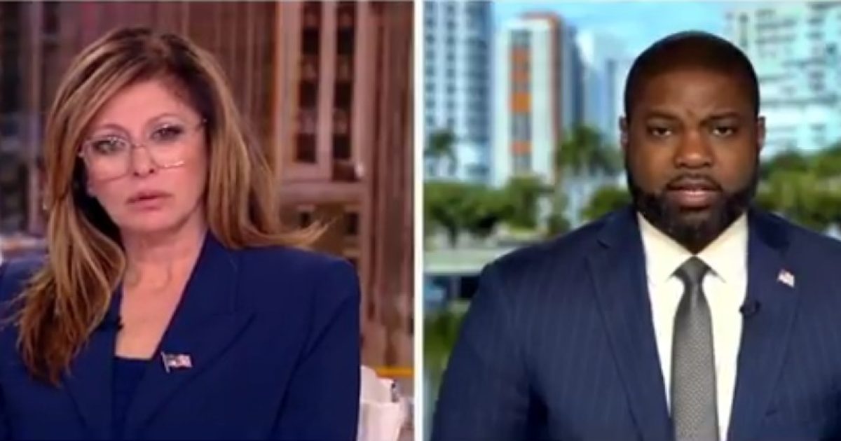 News anchors discussing current events with a city skyline in the background, showcasing a professional television studio setting.