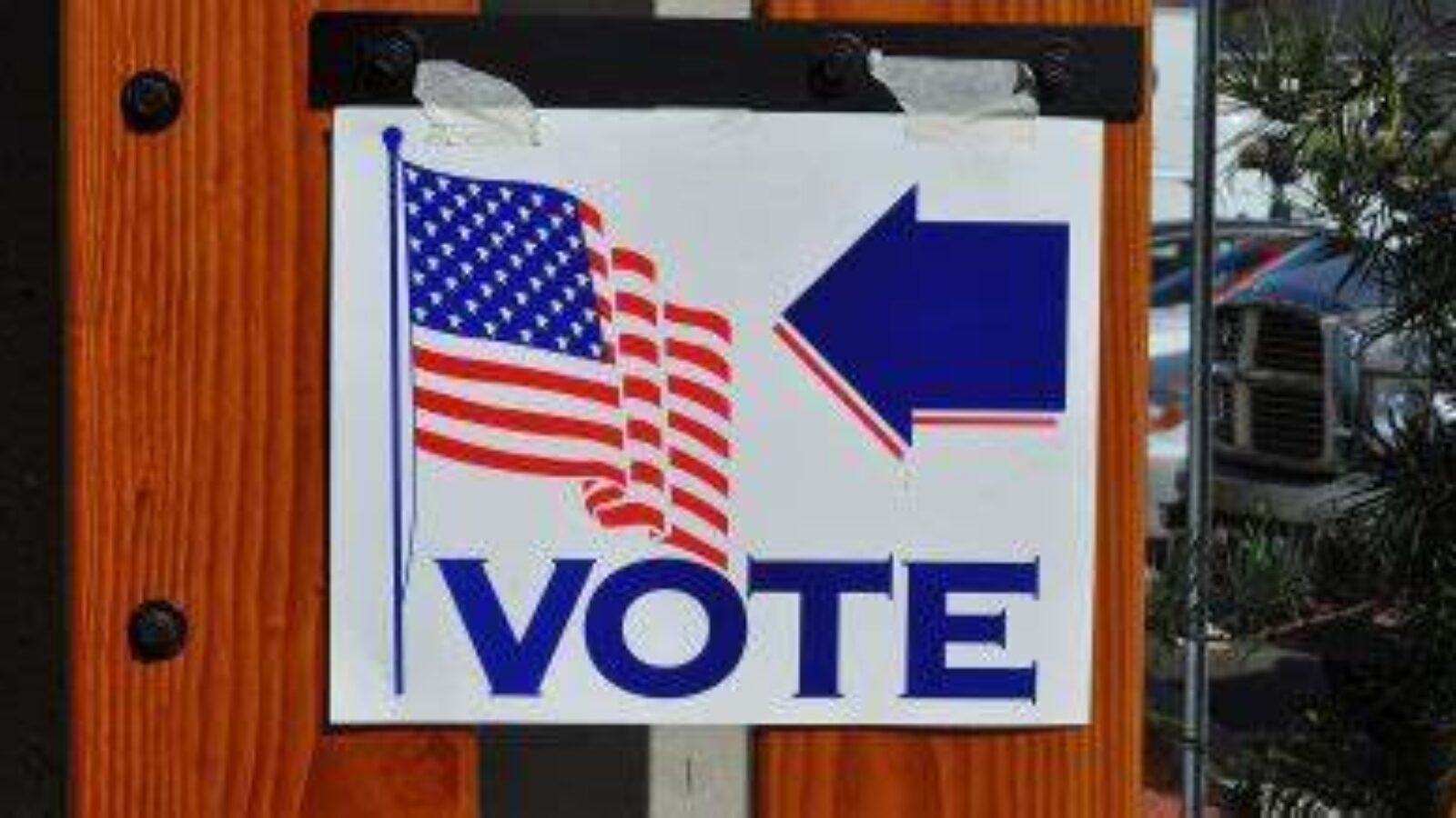 Sign indicating direction to polling place with American flag and the word vote.