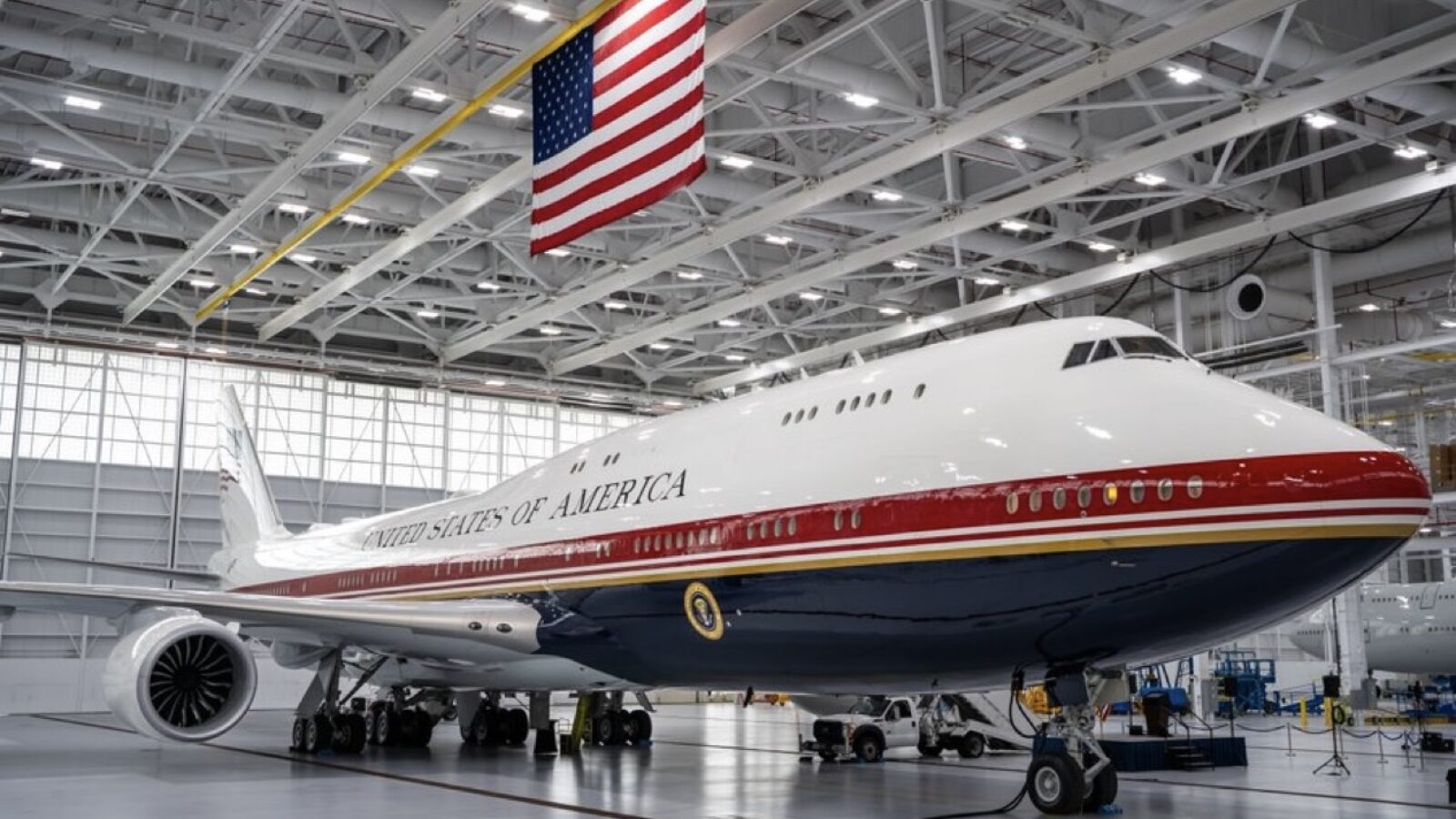 Boeing 747 aircraft designated for the United States government, displayed in a hangar with an American flag overhead.