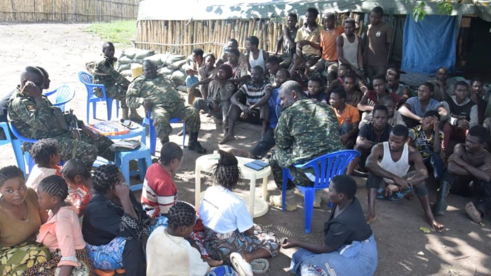 Military personnel engage with a group of local community members in a discussion setting, highlighting interaction and collaboration in a rural environment.