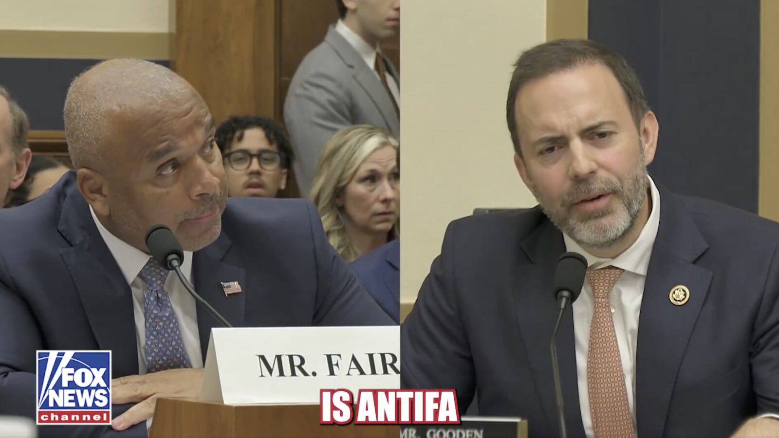 Congressional hearing featuring Mr. Fair and Mr. Gooden discussing the topic of Antifa, with audience members in the background.
