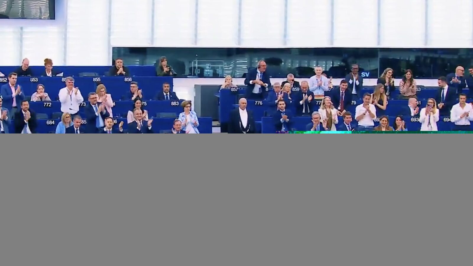 Members of the European Parliament applaud during a session, showcasing a moment of unity and support within the legislative assembly.