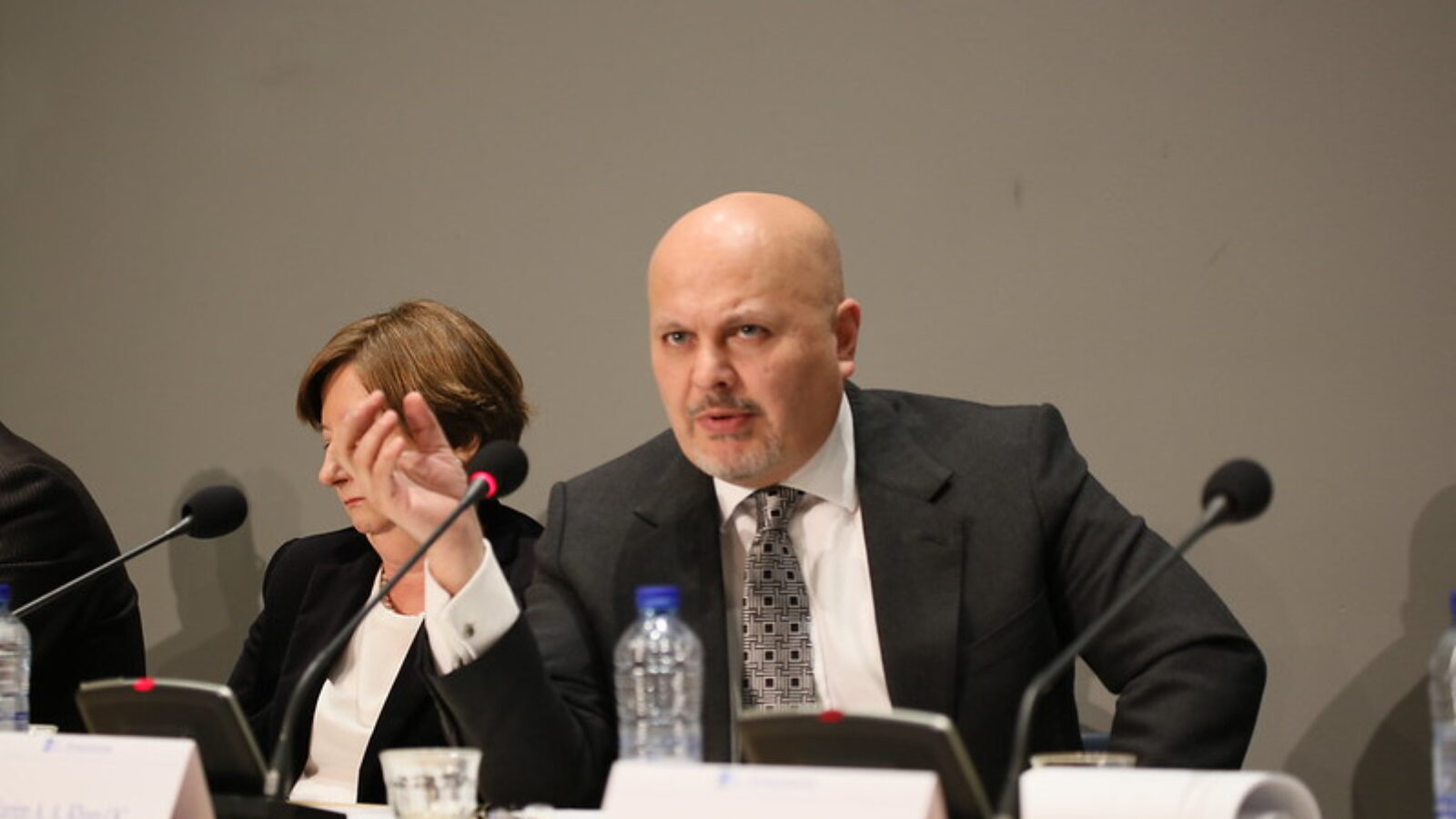 Business professional presenting at a conference, engaging in discussion with colleagues at a panel, showcasing a collaborative atmosphere.