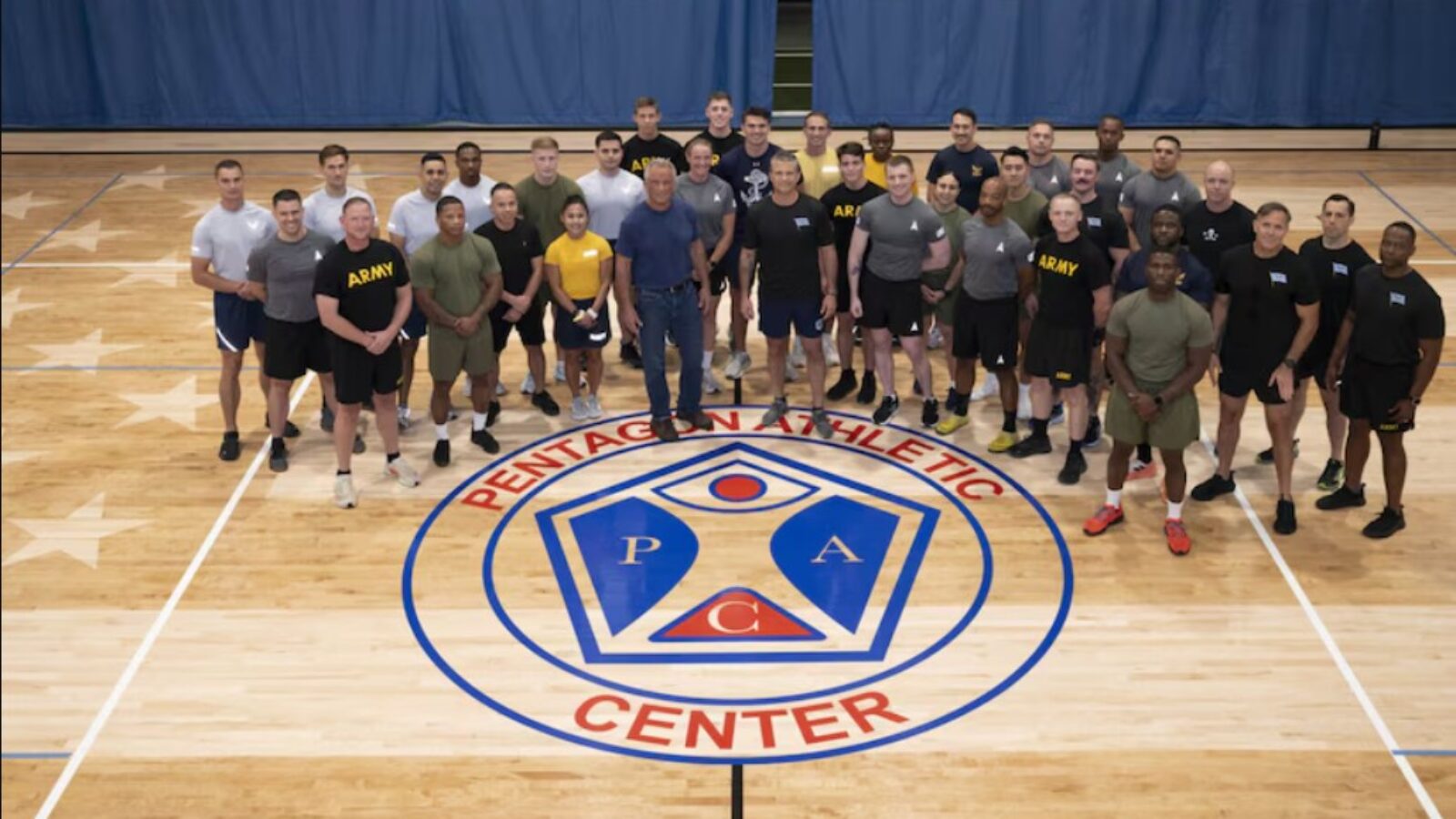 Group photo of military personnel at the Pentagon Athletic Center, showcasing teamwork and camaraderie on a gymnasium floor.