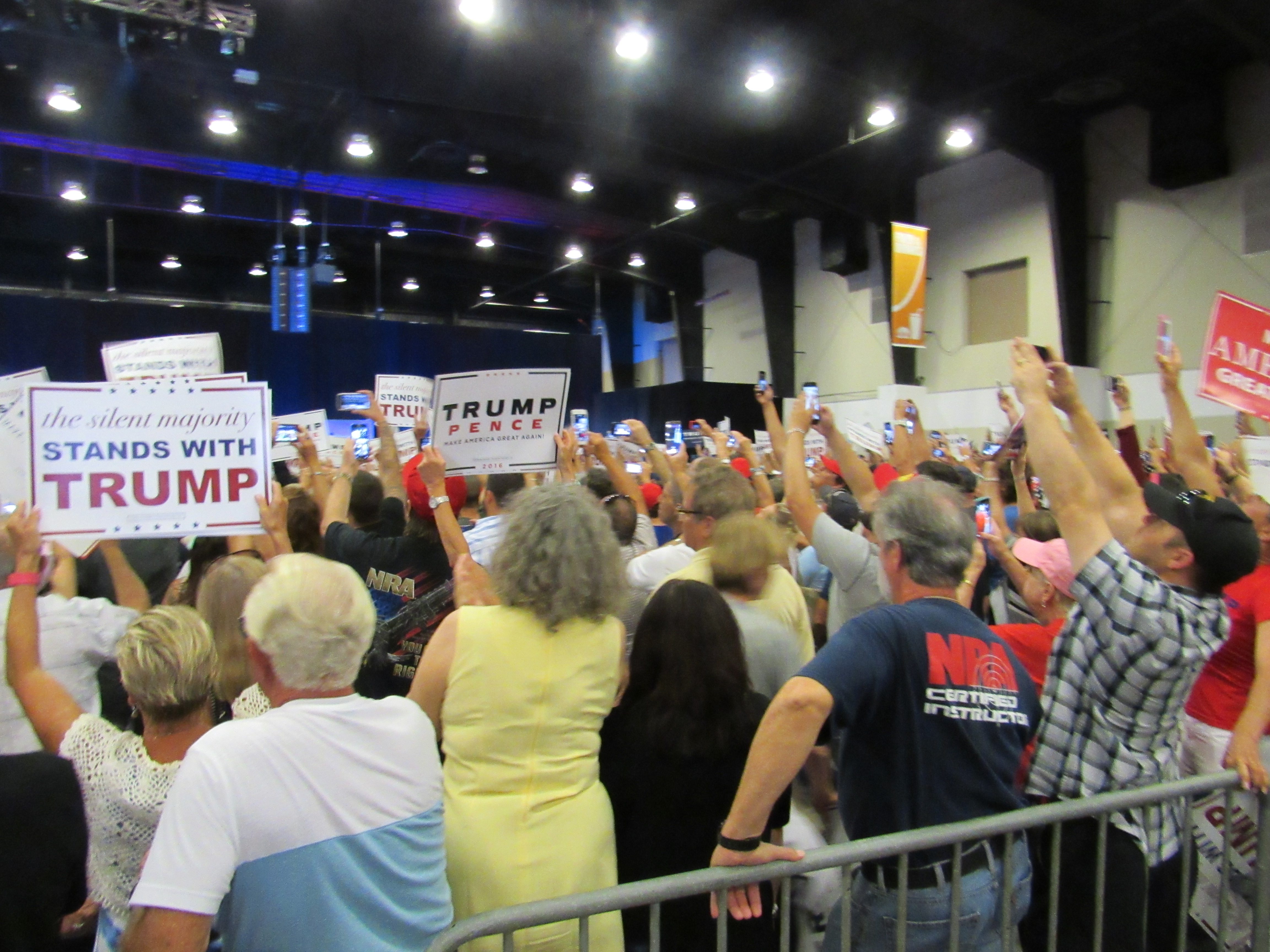 Signs and cellphones held high by supporters as Donald Trump makes entrance at West Palm Beach rally