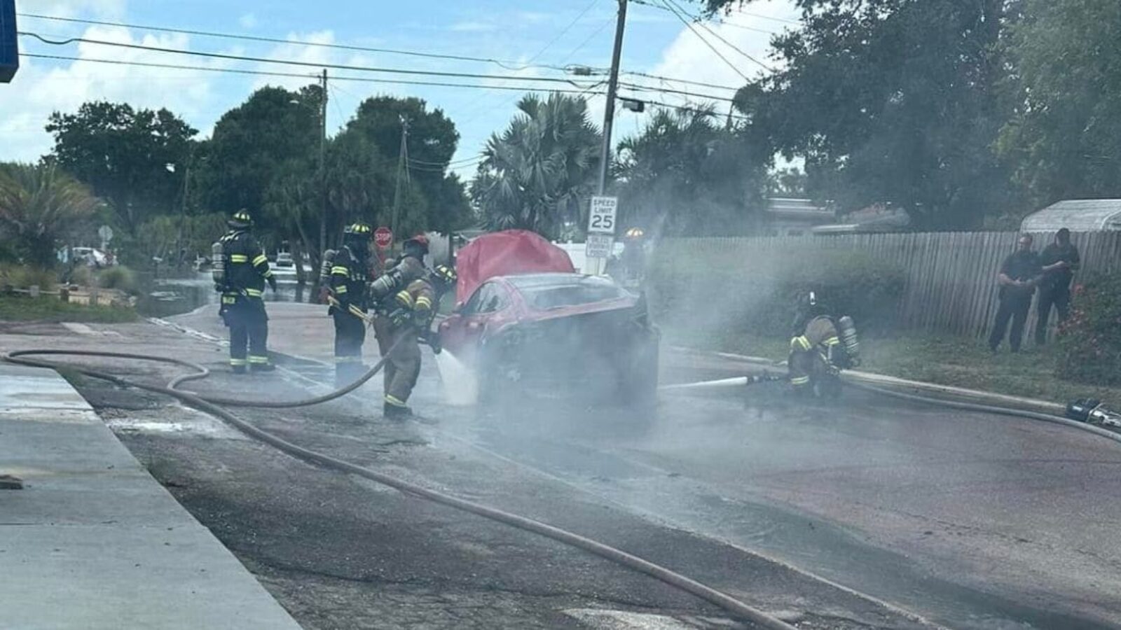firefighters working to extinguish the flames in a burning Tesla